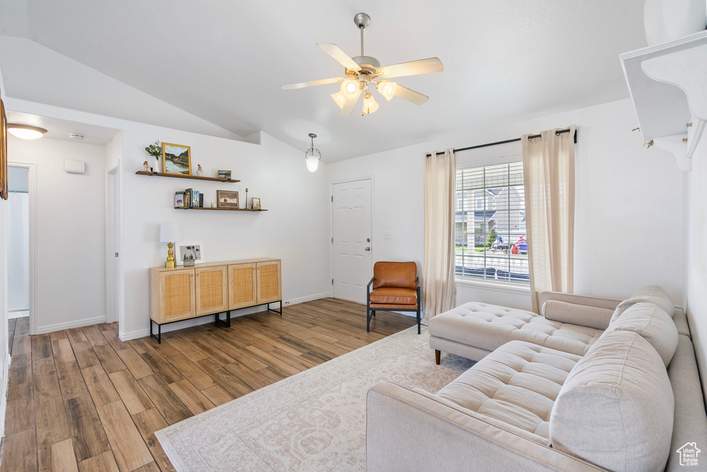 Living room featuring vaulted ceiling, a ceiling fan, wood finished floors, and baseboards