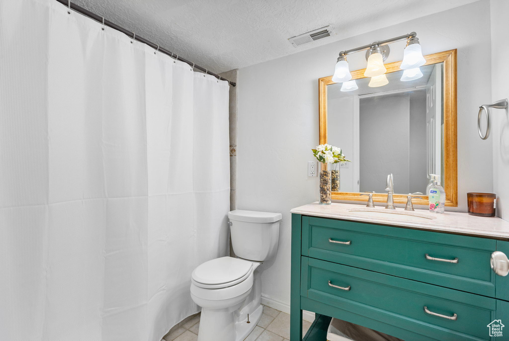 Bathroom with tile patterned floors, visible vents, toilet, vanity, and a textured ceiling
