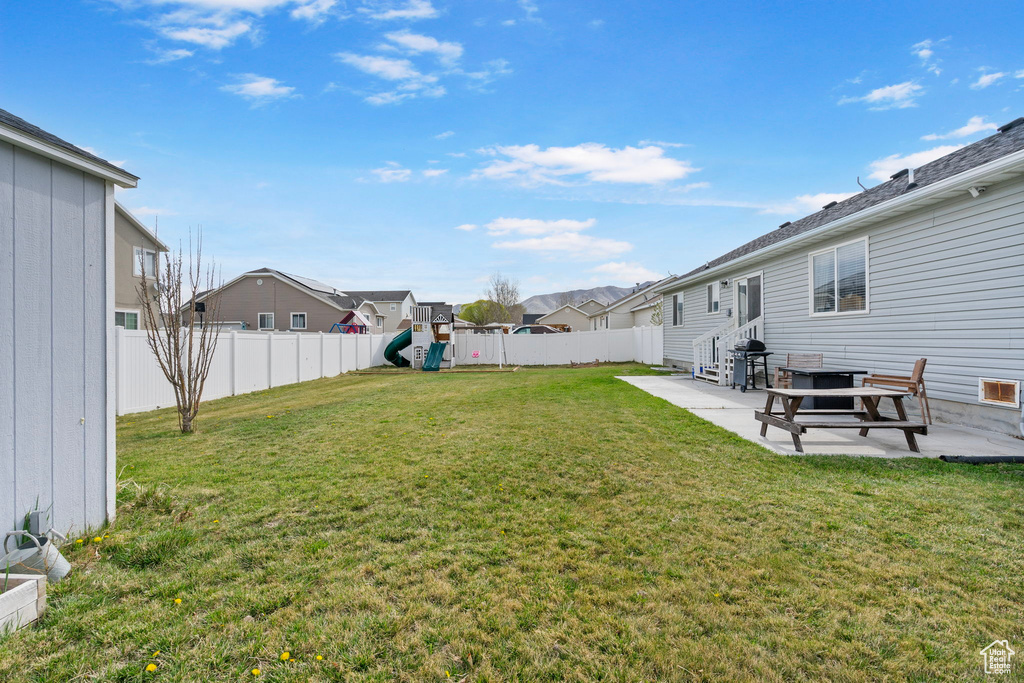 View of yard with a patio area, a playground, a residential view, and a fenced backyard