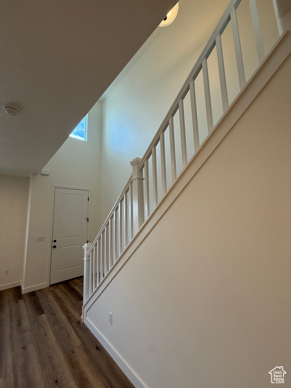 Stairs with wood finished floors, a towering ceiling, and baseboards