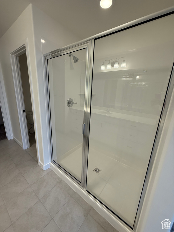 Full bathroom featuring baseboards, tile patterned flooring, a stall shower, and toilet
