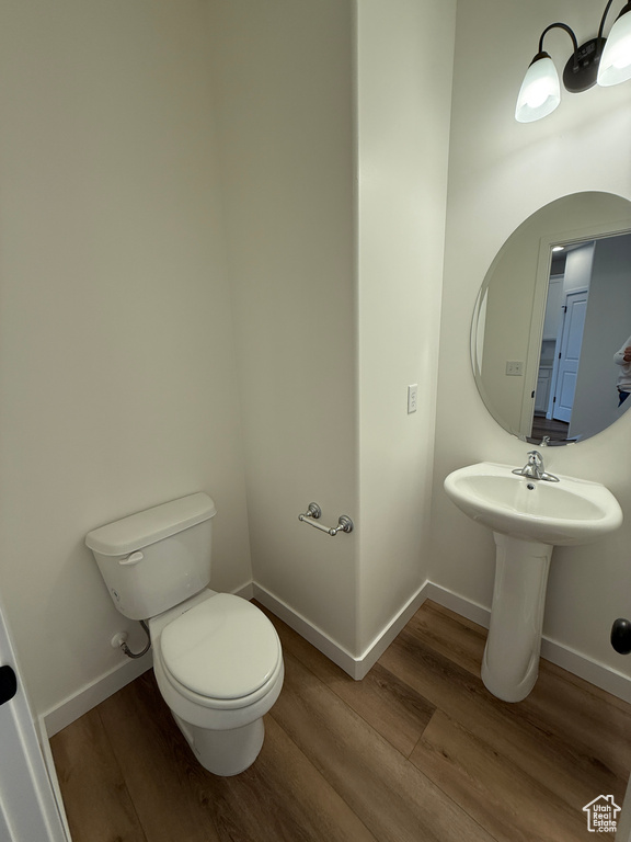 Half bath with baseboards, wood finished floors, and toilet