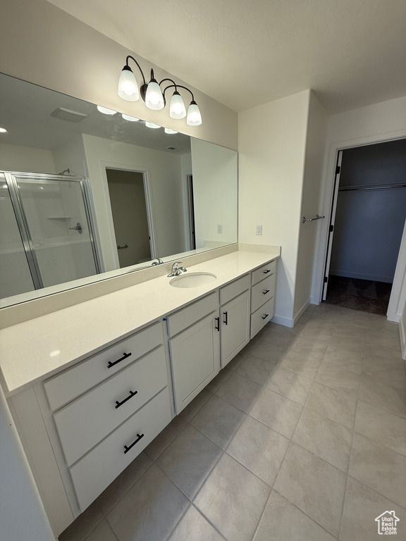 Full bathroom with vanity, tile patterned flooring, a shower stall, and a walk in closet