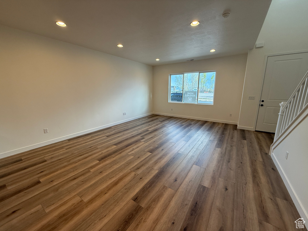Unfurnished living room featuring recessed lighting, baseboards, stairs, and dark wood-style floors