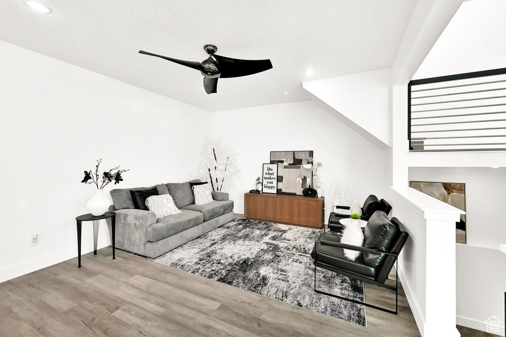 Living room with wood finished floors, ceiling fan, recessed lighting, and baseboards