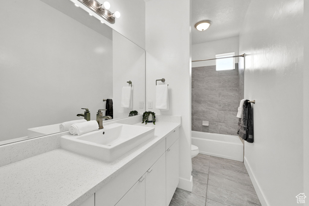 Bathroom featuring vanity, toilet, shower / bathtub combination, and baseboards