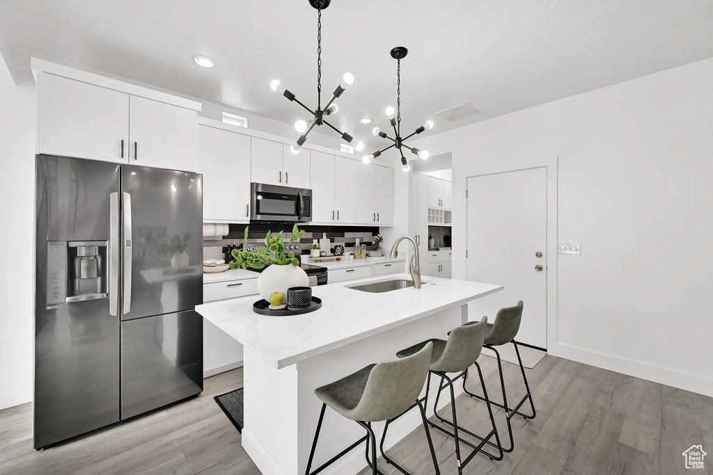 Kitchen featuring appliances with stainless steel finishes, a sink, a chandelier, light wood-type flooring, and recessed lighting