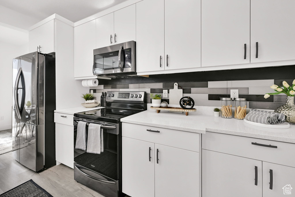 Kitchen featuring stainless steel appliances, white cabinetry, and light wood-style floors