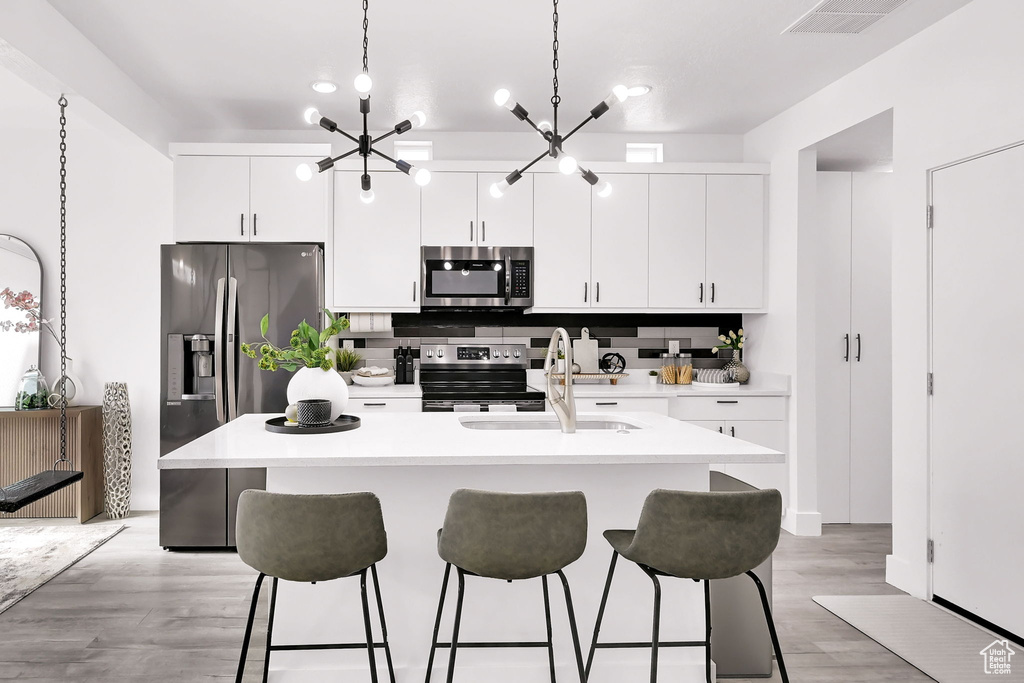 Kitchen with stainless steel appliances, a sink, a breakfast bar area, a kitchen island with sink, and white cabinets