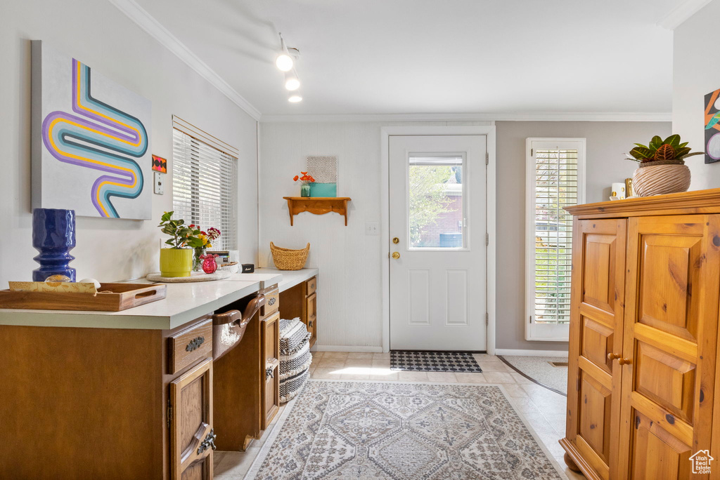Foyer with light tile patterned flooring, rail lighting, crown molding, and baseboards