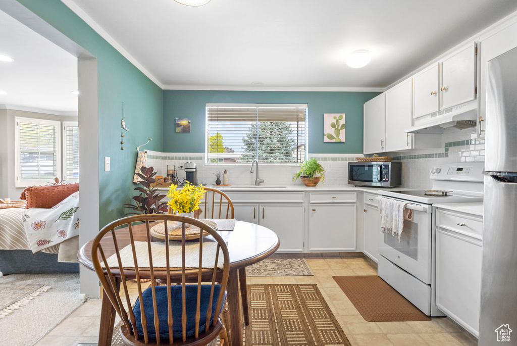 Kitchen with a wealth of natural light, appliances with stainless steel finishes, under cabinet range hood, and a sink