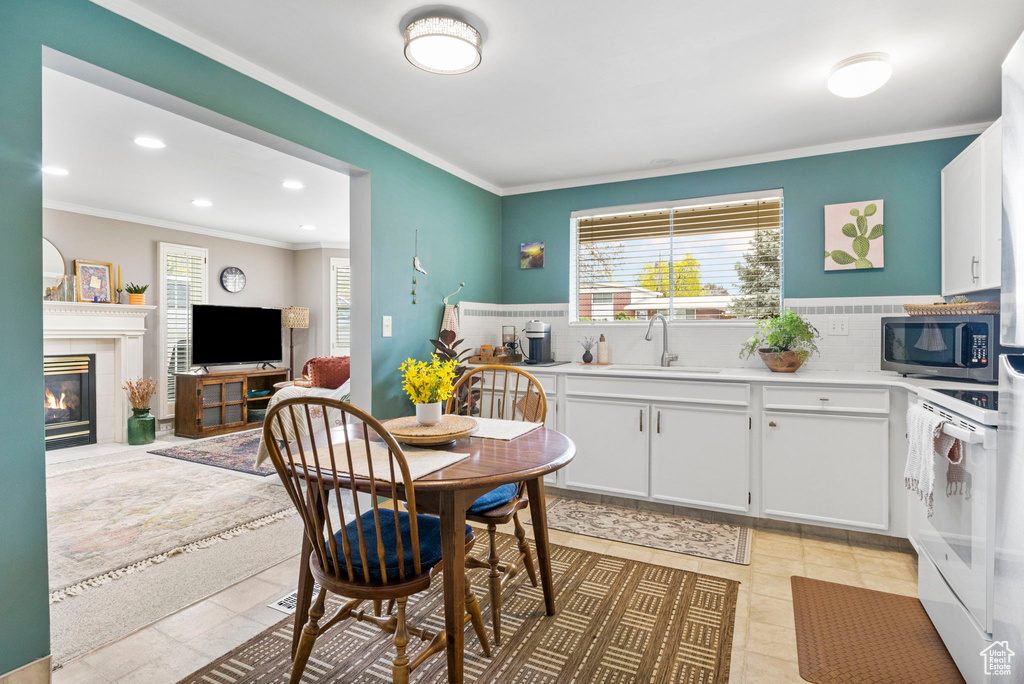 Kitchen with stainless steel microwave, electric stove, crown molding, and a sink