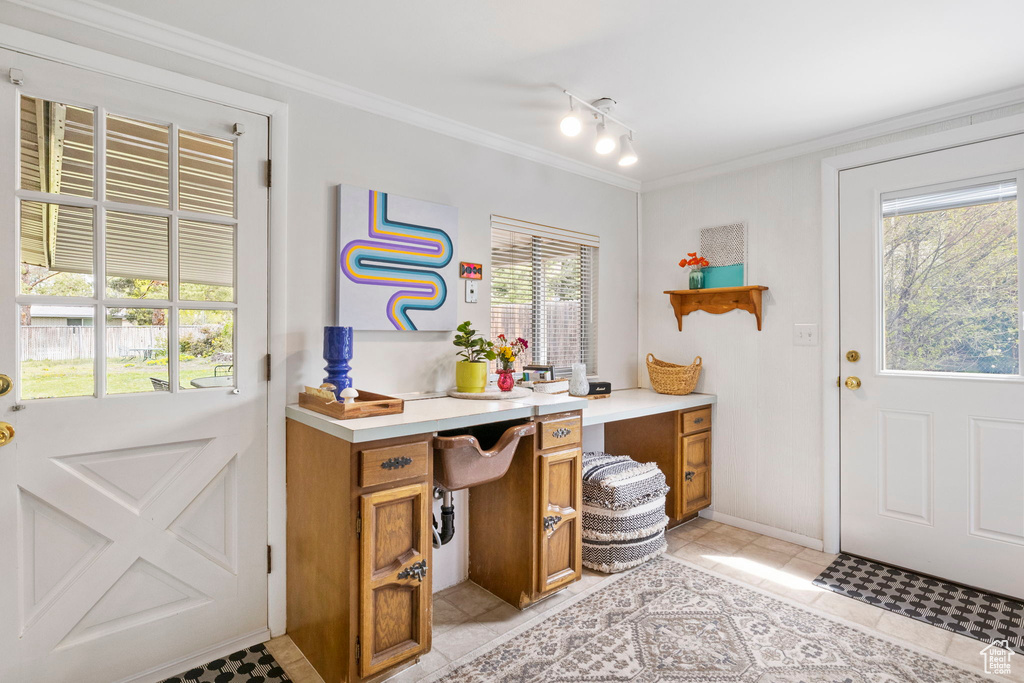 Doorway featuring track lighting, baseboards, ornamental molding, and light tile patterned floors