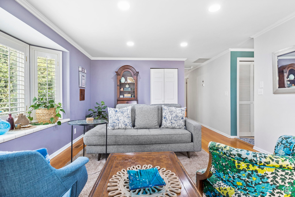 Living room with baseboards, crown molding, wood finished floors, and recessed lighting