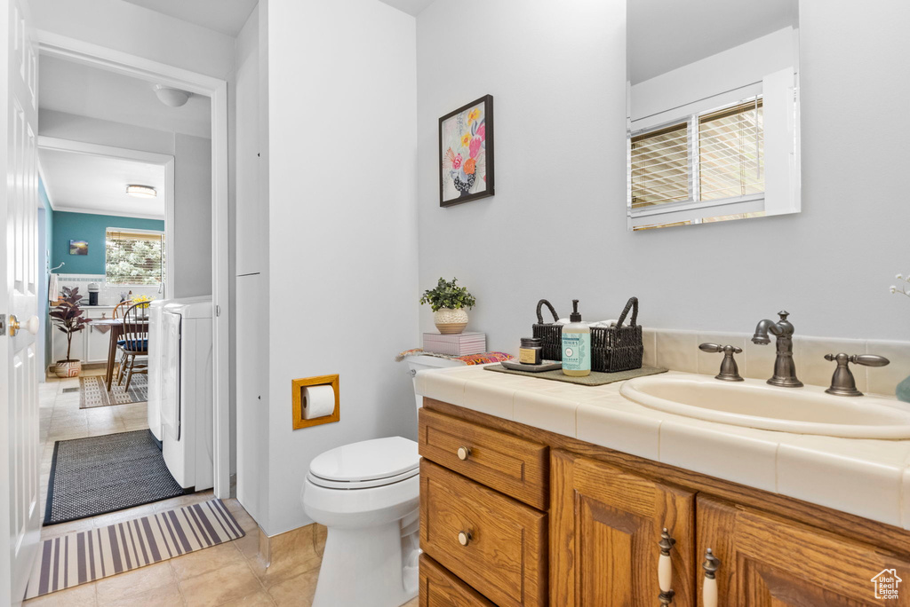 Bathroom with vanity, toilet, washer / dryer, and tile patterned floors