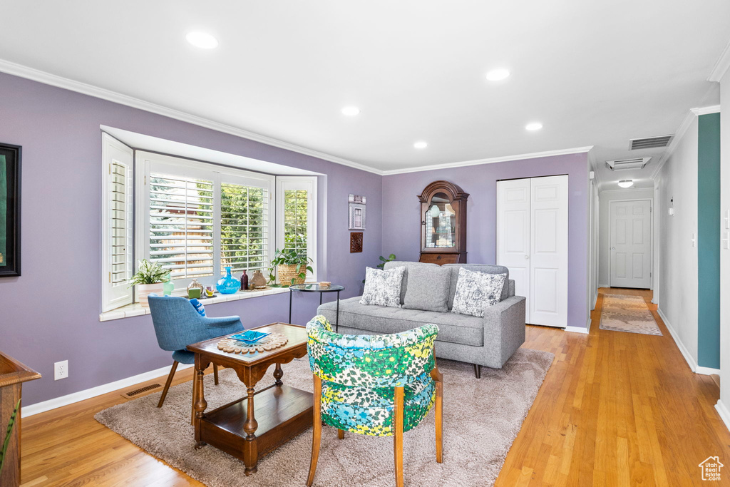 Living room with crown molding, visible vents, and light wood-type flooring