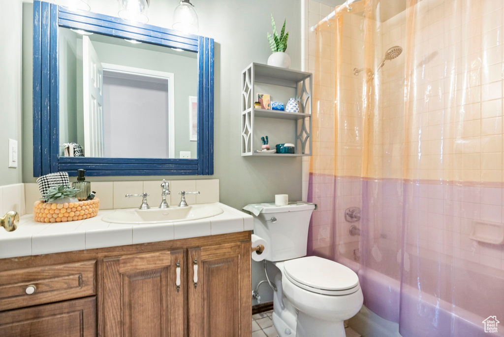 Bathroom featuring toilet, vanity, and shower / bath combo with shower curtain