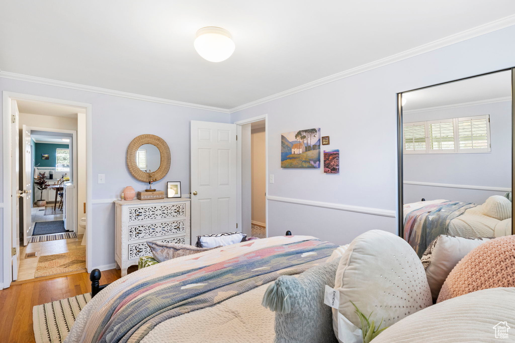 Bedroom featuring baseboards, crown molding, and wood finished floors