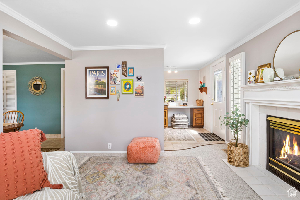 Living room featuring crown molding, light carpet, a tiled fireplace, baseboards, and recessed lighting
