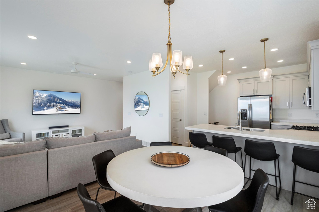 Dining space with a notable chandelier, wood finished floors, and recessed lighting