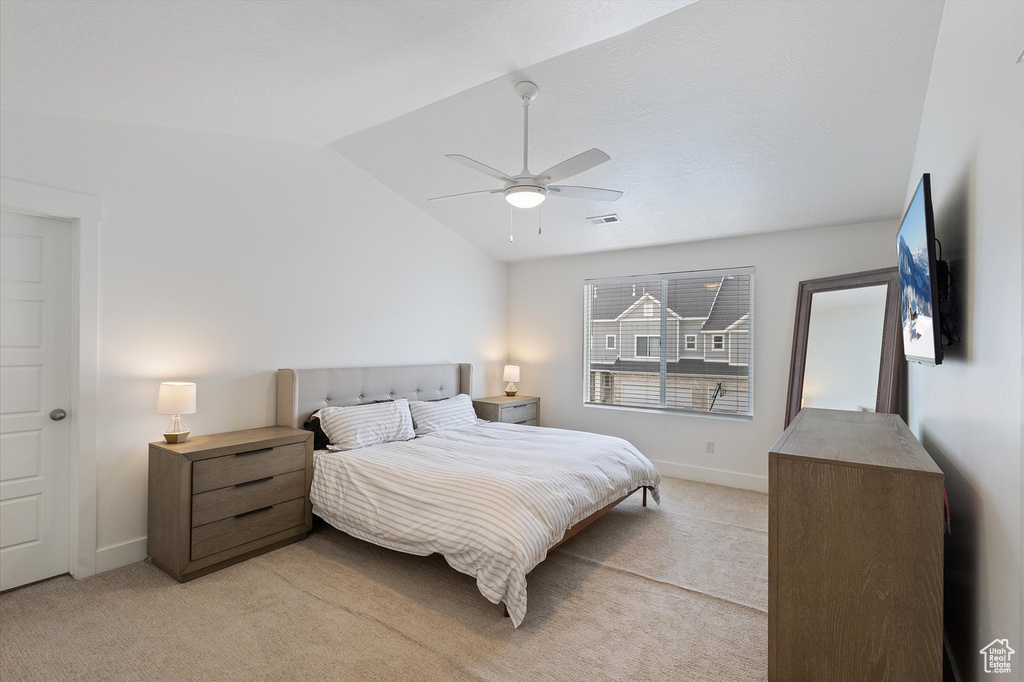 Bedroom with light colored carpet, lofted ceiling, visible vents, and baseboards