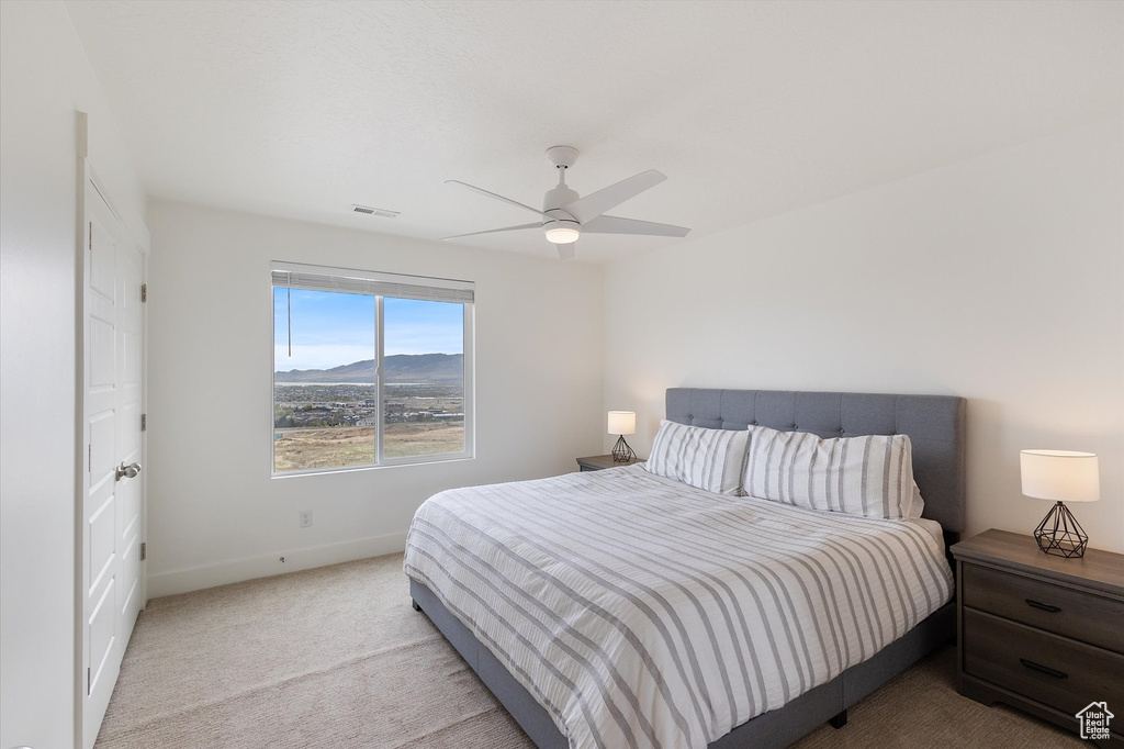 Carpeted bedroom featuring baseboards, visible vents, ceiling fan, and a mountain view