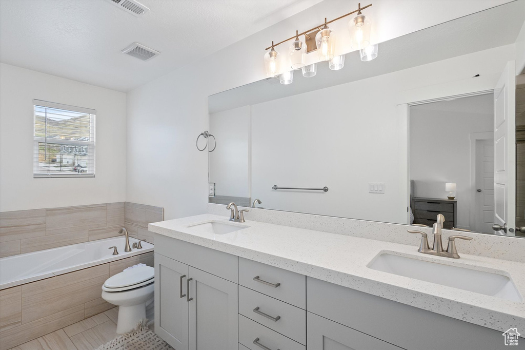 Bathroom featuring a bath, visible vents, toilet, and a sink