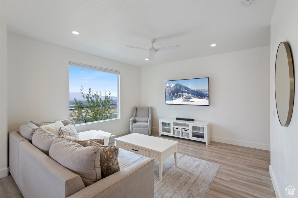 Living room featuring light wood-type flooring, a ceiling fan, baseboards, and recessed lighting