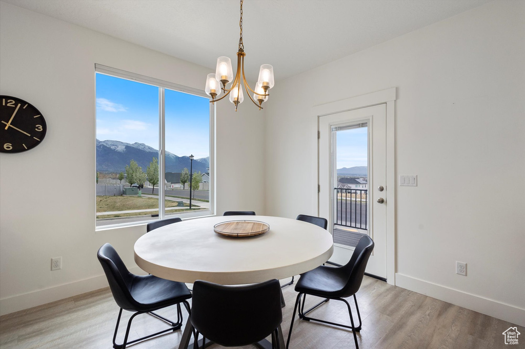 Dining space featuring a chandelier, light wood-style floors, a mountain view, and a healthy amount of sunlight