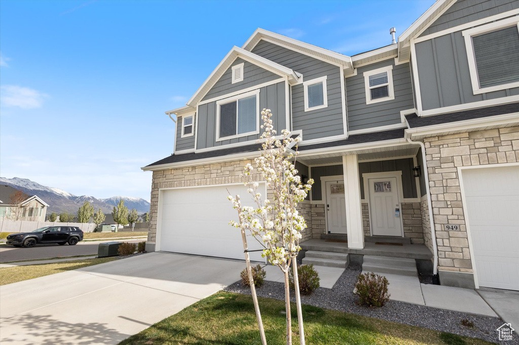 Craftsman inspired home with driveway, stone siding, board and batten siding, an attached garage, and a mountain view