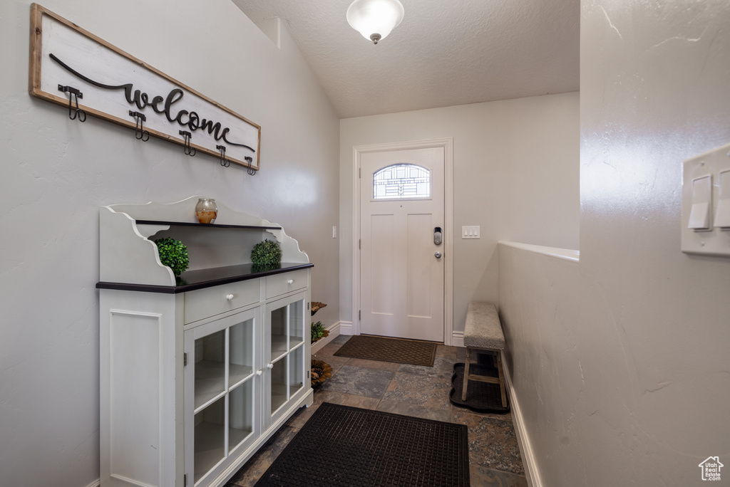 Entrance foyer featuring baseboards, stone finish floor, and a textured ceiling