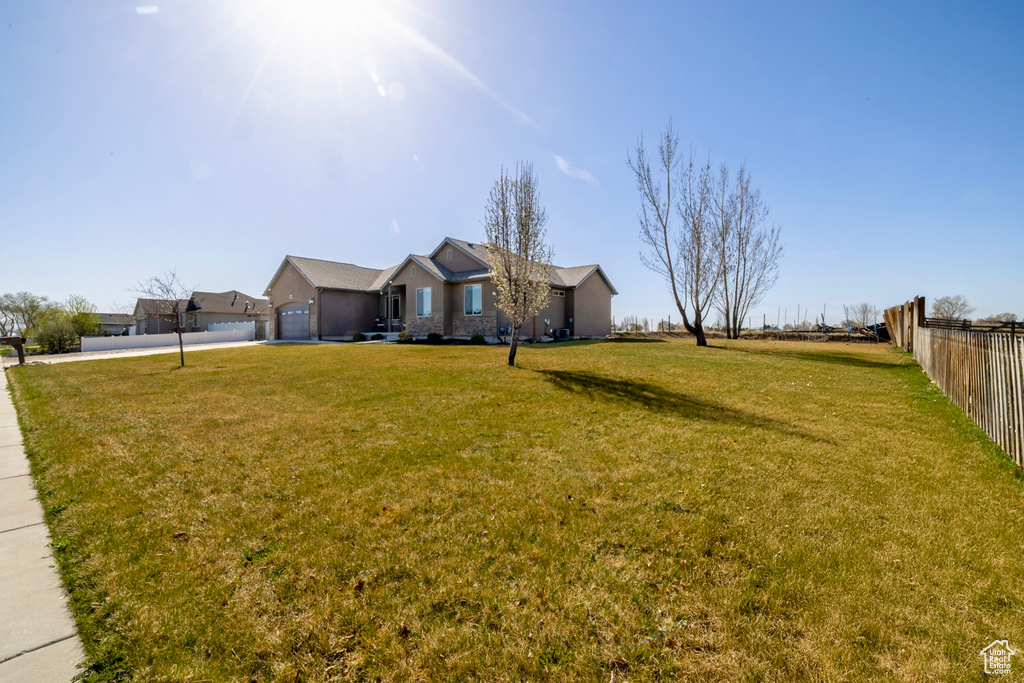 View of yard featuring concrete driveway, a garage, and fence
