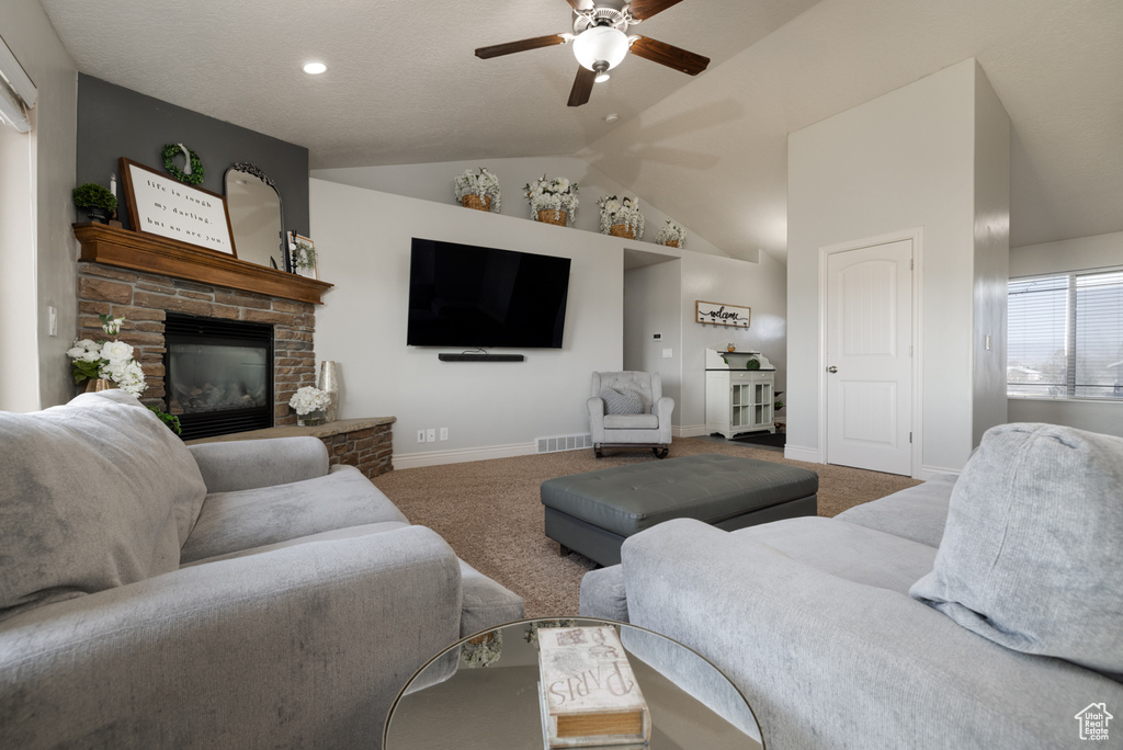 Living room featuring a fireplace, lofted ceiling, a ceiling fan, and carpet floors