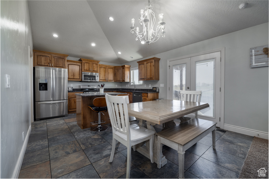 Dining room featuring a notable chandelier, baseboards, french doors, stone tile flooring, and lofted ceiling