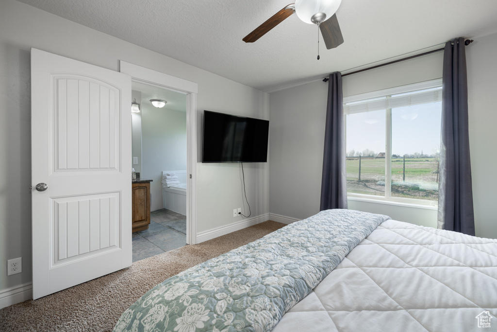 Bedroom featuring ensuite bathroom, baseboards, a ceiling fan, and carpet
