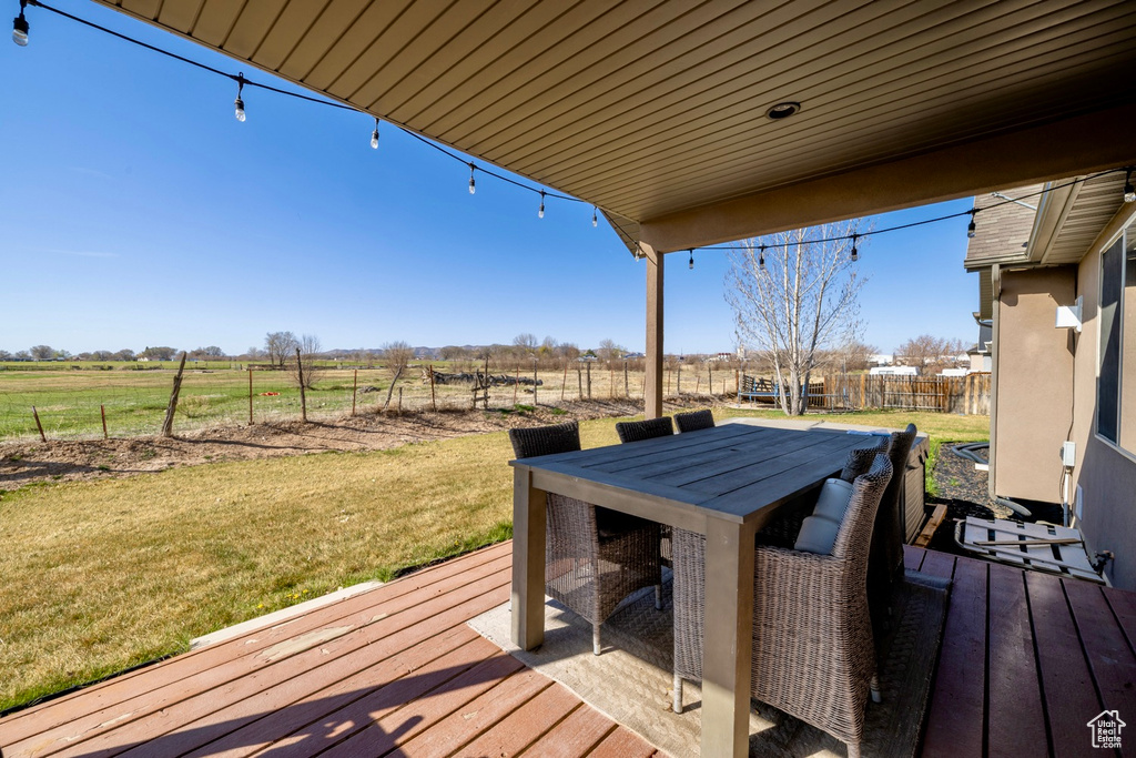 Wooden deck featuring a yard, outdoor dining area, and a rural view