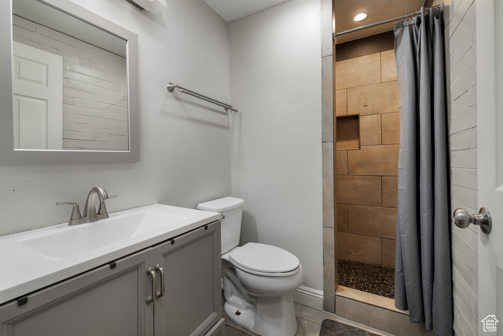 Bathroom with toilet, a tile shower, recessed lighting, and vanity