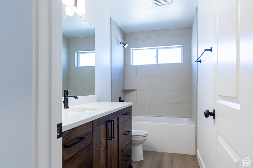Full bath with wood finished floors, visible vents, toilet, vanity, and  shower combination