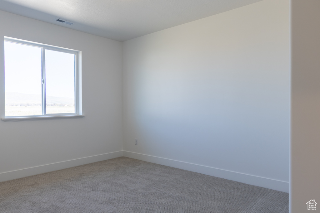 Unfurnished room with visible vents, baseboards, and light carpet