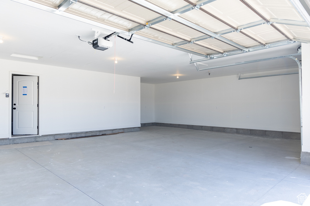 Garage featuring a garage door opener and baseboards