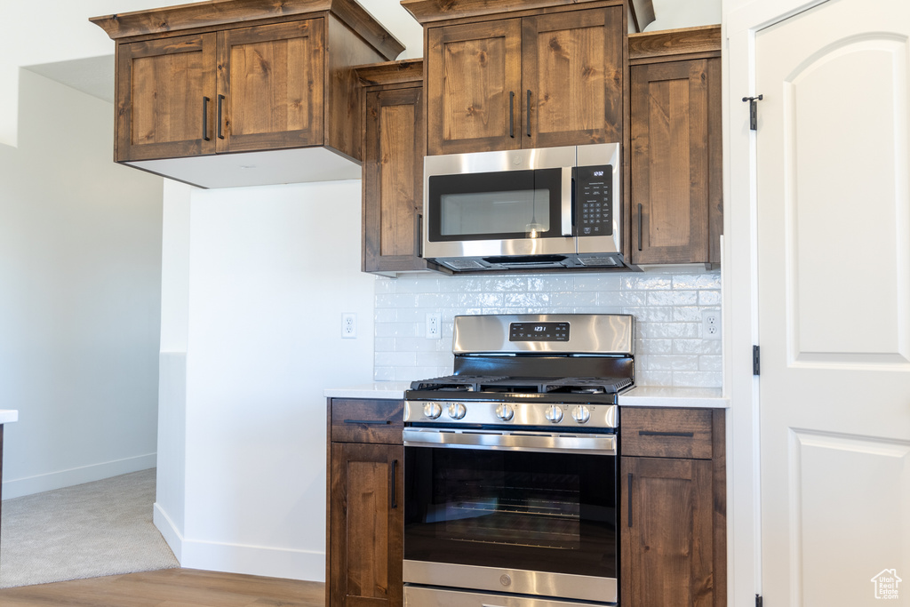 Kitchen featuring baseboards, tasteful backsplash, stainless steel appliances, and light countertops