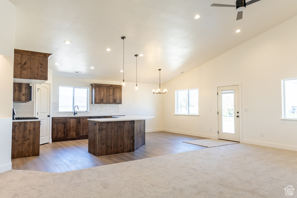 Kitchen with decorative backsplash, plenty of natural light, a kitchen island, and light colored carpet