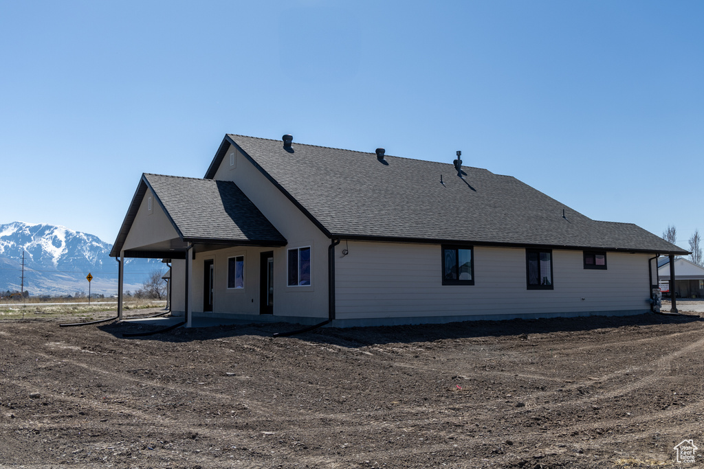 Back of house with a mountain view and roof with shingles
