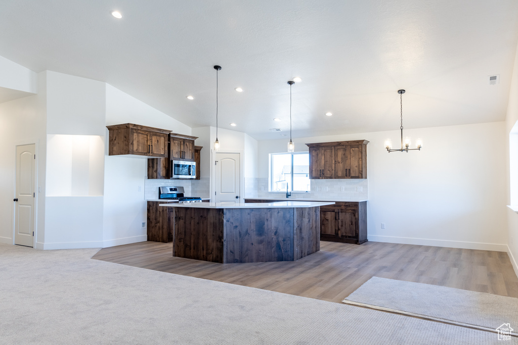 Kitchen featuring backsplash, a notable chandelier, stainless steel appliances, and a kitchen island