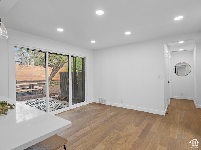 Unfurnished dining area with baseboards, wood finished floors, visible vents, and recessed lighting
