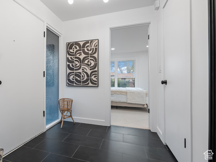 Hallway featuring dark tile patterned floors and baseboards