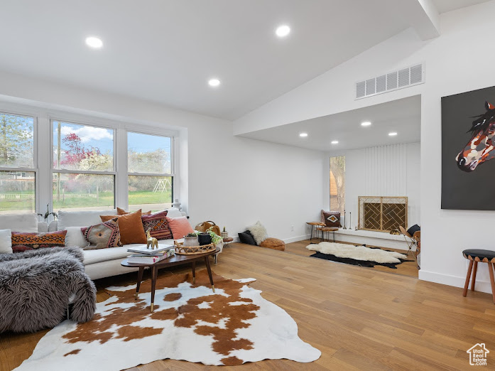 Living room with light wood-style flooring, baseboards, visible vents, recessed lighting, and high vaulted ceiling