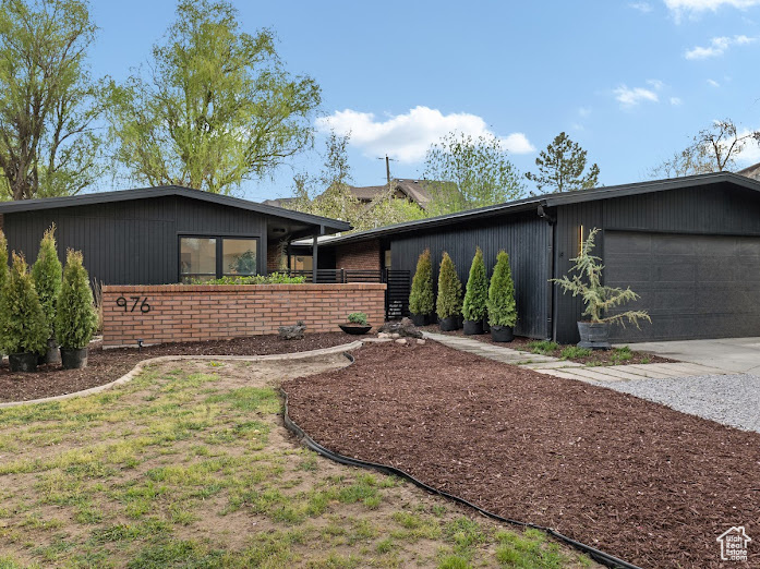 View of front facade featuring an attached garage, fence, brick siding, and concrete driveway