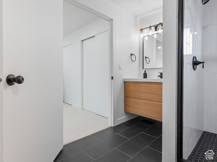 Full bath featuring vanity, tile patterned flooring, and a tile shower