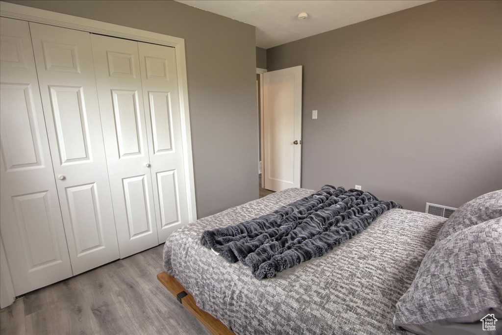Bedroom featuring wood finished floors, visible vents, and a closet